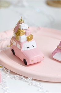 Close-up of pink car ornament with gift boxes and golden string for Christmas tree