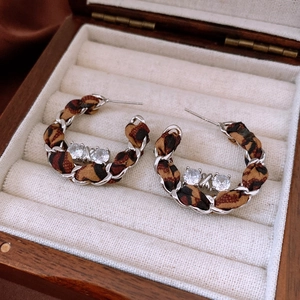 Detailed close-up of C-shaped leopard print fabric and metal chain wrapped earrings
