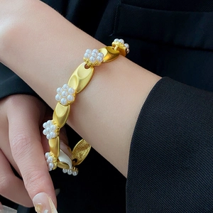 Detailed close-up of vintage gold flower bracelet with white pearls on a wrist