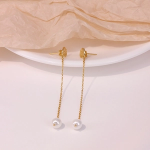 Detail of luxury S925 silver long tassel pearl earrings draped on a ceramic plate