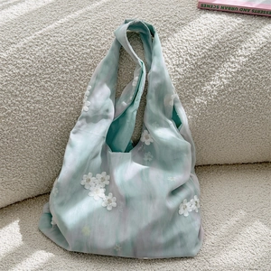 Detailed close-up of white floral embroidery on a green and purple gradient canvas tote bag