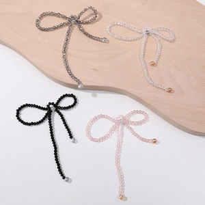 Detail view of four handmade beaded bow charms in grey, clear, black and pink beads