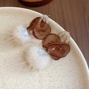 Detail of vintage mesh fur ball earrings with crystals on a ceramic display