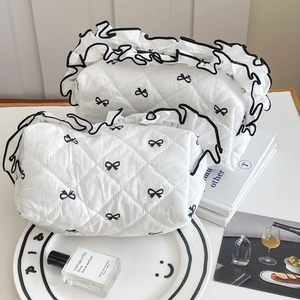Set of two white quilted cosmetic bags with black bow embroidery and ruffled edges
