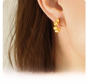 Close-up of 18k gold plated surgical titanium steel C-shaped beaded hoop earring on ear