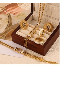Détail d'un ensemble de bijoux en titane doré avec chaînes torsadées et boucles tournesol