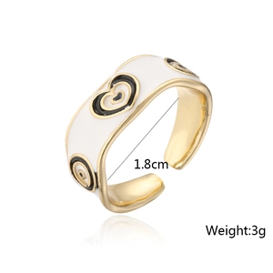 Detail shot of heart and evil eye enamel patterns on a gold-plated open ring