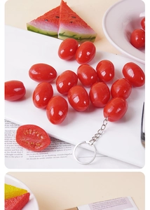 Realistic cherry tomato keychain with glossy finish displayed on a white tray with props