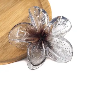Macro detail of frangipani flower hair claw clip with grey gradient and glitter finish