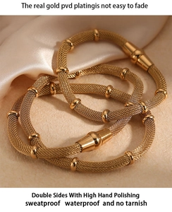 Detail of gold PVD plated mesh chain bracelet with magnetic clasp on silk background