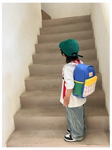 Detailed back view of a colorful canvas backpack for kids on stairs showing wide straps