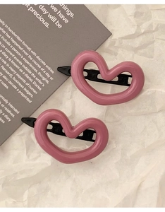 Vue détaillée de deux pinces à cheveux roses en forme de cœur sur papier blanc texturé