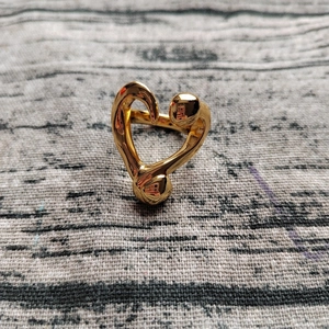 Macro shot of abstract fluid heart ring with polished golden finish on textured background