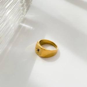 Detail of a gold signet ring featuring a black zircon center star and polished finish