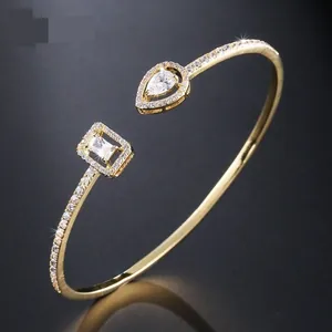 Detail of gold-plated open bangle with micro-pave cubic zirconia and pear-cut charms