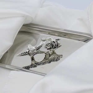 Close-up of vintage punk skull ring with movable joints on a silver tray with white satin