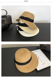 Close-up of woven straw sun hats in brown and beige with black ribbon bow details
