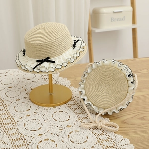 Detail of straw sun hat and matching bag set with white lace and black ribbon bow