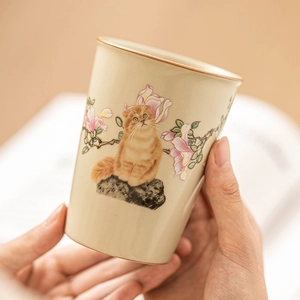 Ru-kiln ceramic teacup with hand-painted ginger cat and pink flowers in warm setting