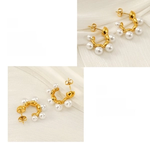 Close-up of C-shaped pearl earrings with polished gold plating on silk background