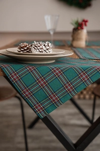 Detail of Christmas plaid placemat with pinecones and berries on a rustic wooden table