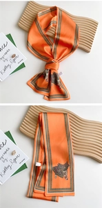 Detailed view of orange twilly silk scarf with vintage saddle print and striped borders