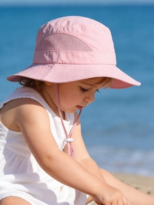 Pink kids sun hat with breathable side mesh and adjustable chin strap at the beach