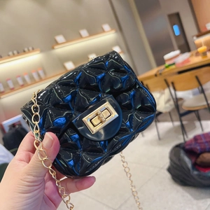 Detalle del mini bolso de gelatina acolchado negro con cadena dorada y cierre de giro