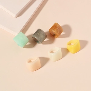 Minimalist square resin rings in assorted marble and solid colors on a pink background