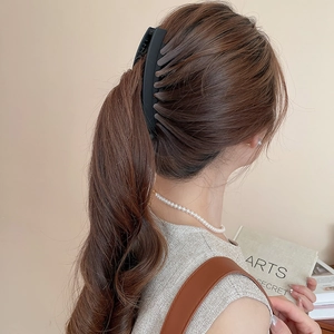 Gros plan d'une pince à cheveux noire mate fixant une queue de cheval sur un mannequin