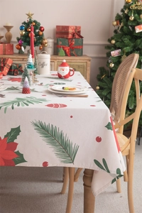 Detailed view of Christmas tablecloth with pine needles and red berries on a wooden table