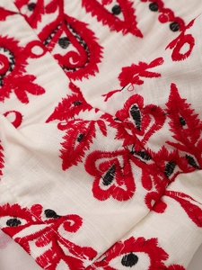 Détail macro d'une broderie bohème rouge sur un short décontracté en coton et lin
