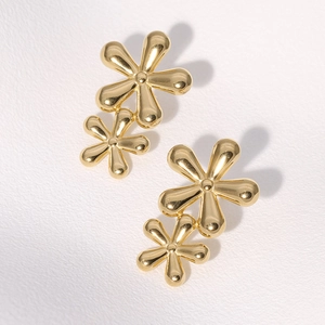 Detailed view of golden double-layer flower stud earrings with a smooth metallic finish
