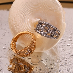 Close-up of gold and silver braided chain rings with cubic zirconia on a wet surface