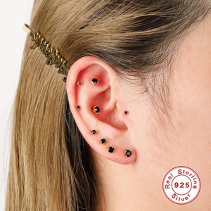 Detail showing set of gold S925 silver stud earrings with black stones on ear
