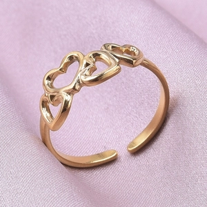 Detail of gold heart-shaped ring featuring four hollow hearts on pink silk backdrop