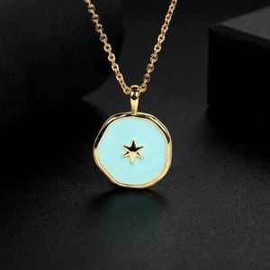 Close-up of gold chain necklace with blue enamel coin pendant and gold star detail