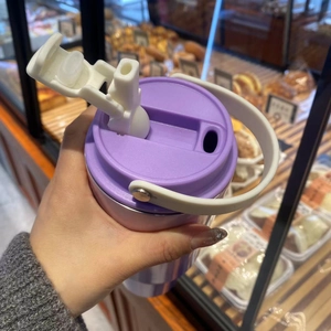 Detail view of the purple travel mug lid with a white handle and dual-drinking straw top