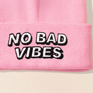 Pink knitted beanie hat featuring NO BAD VIBES embroidery in a streetwear style