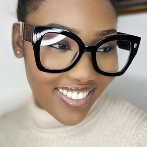 Close-up of black oversized cat-eye glasses with transparent lenses on a female model