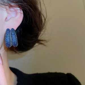 Macro detail of double-layer U-shaped hoop earrings with sparkling blue zircon stones