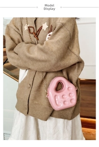 Mini pink jelly crossbody bag with gold chain strap shown on a beige knit cardigan