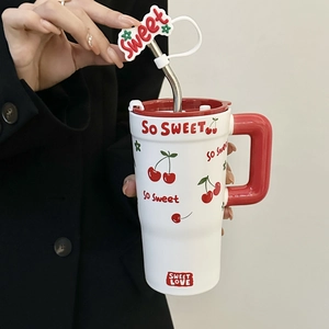 Close-up of a white ceramic mug featuring a red handle and sweet cherry patterns with straw