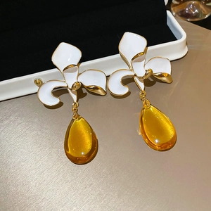 Macro detail of vintage floral earrings with amber resin water drop tassels and gold edges