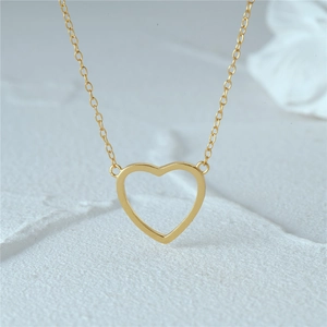 Detailed close-up of golden heart pendant necklace on minimalist stone texture background