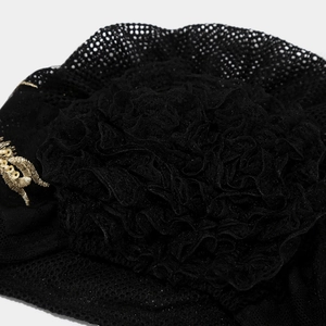 Close-up of black lace mesh turban hat with floral folds and gold sequin embroidery