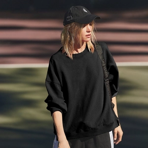 Detail shot of black crewneck sweatshirt showing fabric texture in natural light