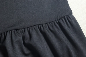 Vue macro du tissu noir avec plis détaillés et coutures soignées sur la robe