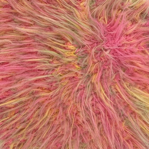 Primer plano de la suave textura de piel sintética rosa y amarilla de un gorro de invierno