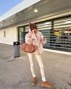 Pink faux fur coat with brown beanie and snow boots in a stylish winter street outfit